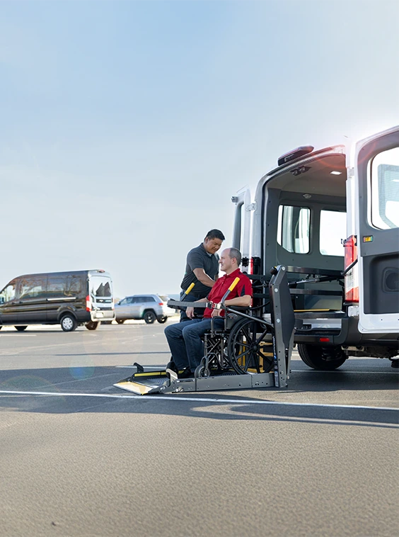 Wheelchair user being lifted into the white shuttle bus on a parking lot
